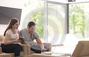 Couple relaxing at home with tablet and laptop computers