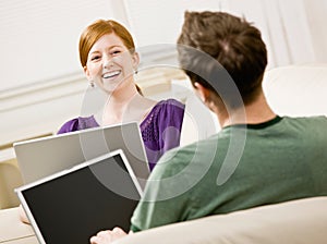 Couple relaxing in livingroom typing on laptops