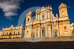 Couple relaxing on the monumental staircase at Noto cathedral, Sicily, Italy