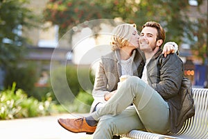 Couple Relaxing On Park Bench With Takeaway Coffee