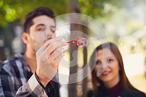 Couple Relaxing in the Park with bubble blower. Spring time.