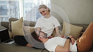 Couple relaxing on sofa together enjoying their relationships and have a talk. Blonde woman and man is lying on her