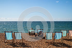 A couple relaxing on the striped chairs in Brighton beach