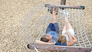 Couple relaxing in a tropical hammock in a city amusement park. do selfie on the camera. 4k. space for copying