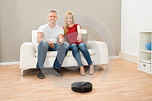 Couple With Remote Control And Robotic Vacuum Cleaner