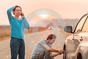 Couple repairing car flat tire on the road