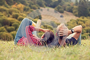 Couple rest in green grass on the hill in country side