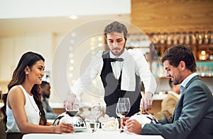 Couple, restaurant server and fine dining at table for valentines day date, bonding and romance in night. Man, woman and