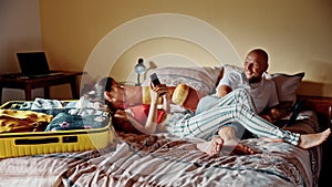 Couple resting in bed before roadtrip. Halfway through packing suitcase family couple discussing plans and expectations