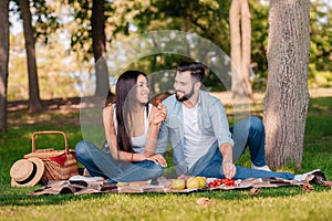 Couple resting on blanket while having picnic together