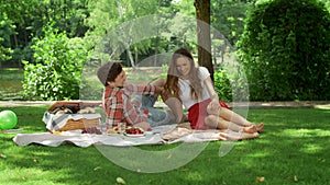 Couple resting on blanket in park. Woman and man having conversation at date