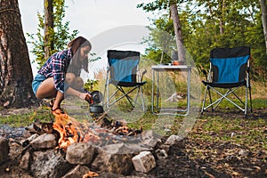 couple resting near bonfire. woman cooking outdoors on fire