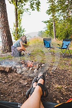 couple resting near bonfire. woman cooking outdoors on fire