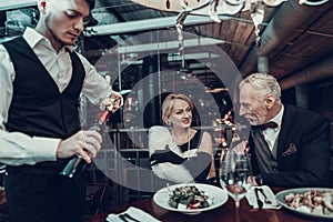 Couple Resting in Restaurant and waiter open wine