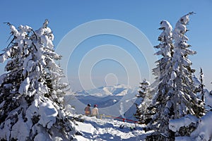 A couple is resting at a ski resort with beautiful view to the snowy mountains.