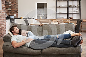 Couple Resting On Sofa In Open Plan Lounge