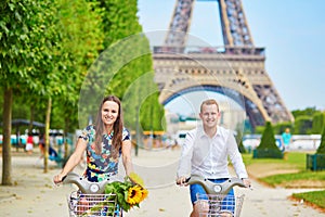 Couple riding bicycles near the Eiffel tower in Paris