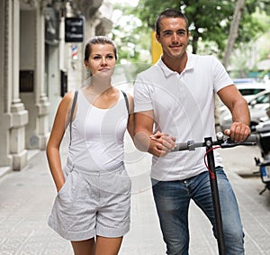Couple riding electro scooter on streets