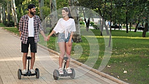 Couple riding hoverboards and holding hands