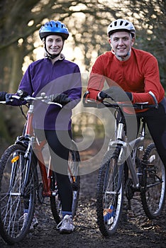 Couple Riding Mountain Bikes Through Woodlands photo