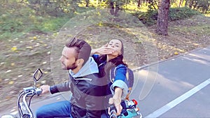 Couple riding a scooter. Selfie-stick shooting. Slow motion.