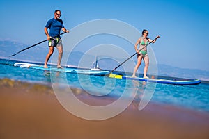 Couple riding SUP stand up paddle on vacation