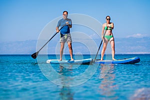 Couple riding SUP stand up paddle on vacation