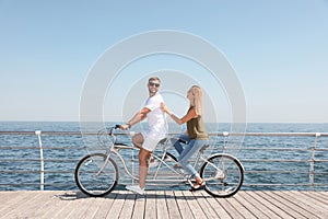 Couple riding tandem bike near sea