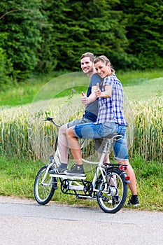 Couple riding tandem bike together in the country