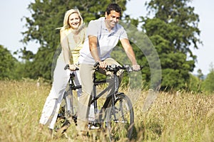 Couple riding tandem in countryside