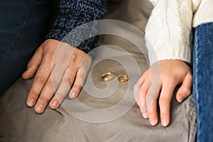 Couple with rings sitting on sofa, closeup. Concept of divorce