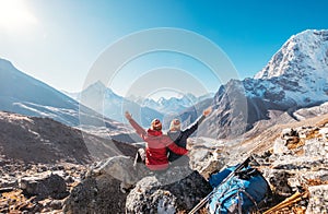 Couple rising arms rejoicing Everest Base Camp trekking route near Dughla 4620m. Backpackers left Backpacks and trekking poles and