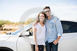 Couple on road trip standing by the car