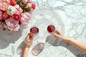 Couple on romantic date. Friends clinking glasses, top view. Red wine, flowers around on wooden table. Wedding celebration, party