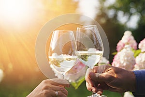 Couple romantically celebrate outdoors with glasses of white wine, proclaim toast People having dinner in a home garden
