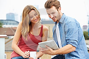 Couple On Roof Terrace Using Digital Tablet