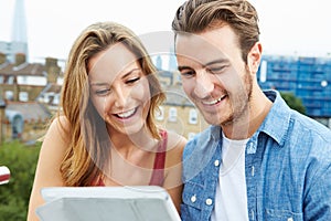 Couple On Roof Terrace Using Digital Tablet