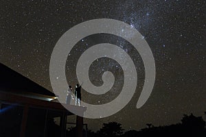 Couple on rooftop watching mliky way and catching stars in the night sky on Bali island