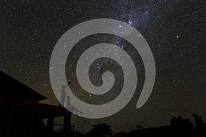 Couple on rooftop watching mliky way and catching stars in the night sky on Bali island