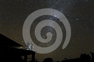 Couple on rooftop watching mliky way and stars in the night sky on Bali island