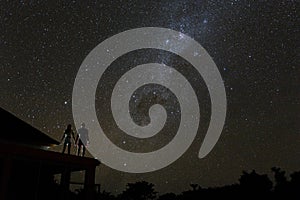 Couple on rooftop watching mliky way and stars in the night sky on Bali island