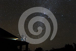 Couple on rooftop watching mliky way and stars in the night sky on Bali island