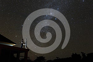 Couple on rooftop watching mliky way and stars in the night sky on Bali island