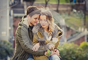 Couple with rose in love kissing on street alley celebrating Valentines day with passion sitting on city park