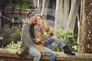 Couple with rose in love kissing on street alley celebrating Valentines day with passion sitting on city park