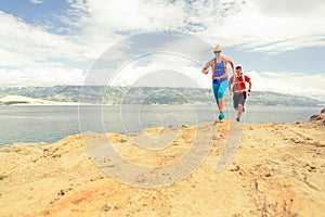 Couple runners running with backpacks on rocku trail at seaside