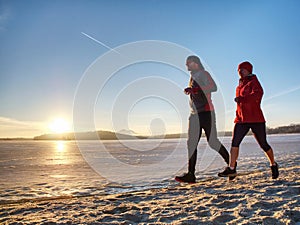 Couple runners running in winter nature. Frozen river