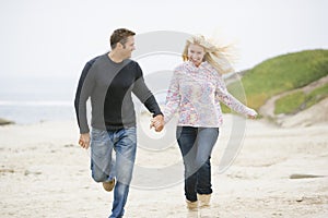 Couple running at beach holding hands