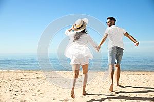 Couple running on beach near sea. Honeymoon trip