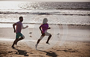 Couple running on beach. Silhouette of young man and woman running jogging along the sea.